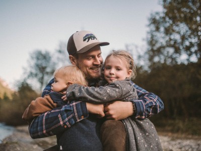 Ein Vater hat seine Kinder im Arm, neben dem Feuerstein am Bach