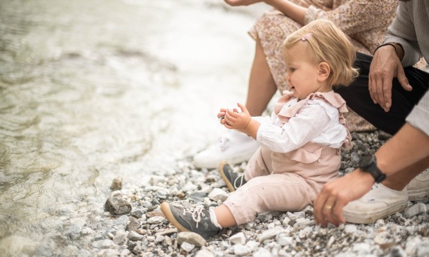 Eine Mutter sitzt mit ihrem Baby auf einem flauschigen Teppich, umgeben von weichen Kissen.