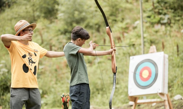 Dipendente istruisce un ragazzo nel tiro con l’arco davanti a un bersaglio al Feuerstein.