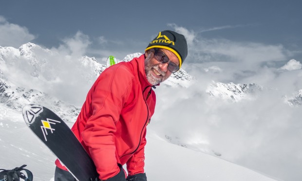 Uno sciatore con uno sci in mano in mezzo alla montagna innevata