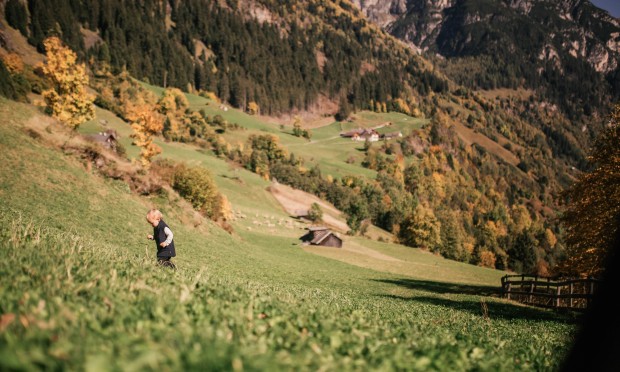 Un bambino passeggia attraverso il prato autunnale.