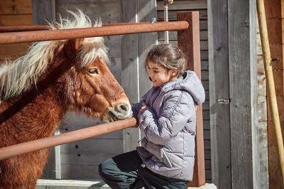 Mädchen streichelt das Pony im Familienhotel Feuerstein in Südtirol