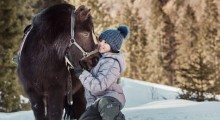 Kind mit Pony im Schnee im Familienhotel Feuerstein in Südtirol
