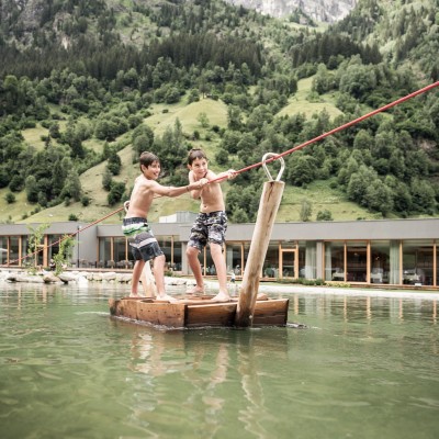 2 Jungs ziehen sich auf Floß über den Teich