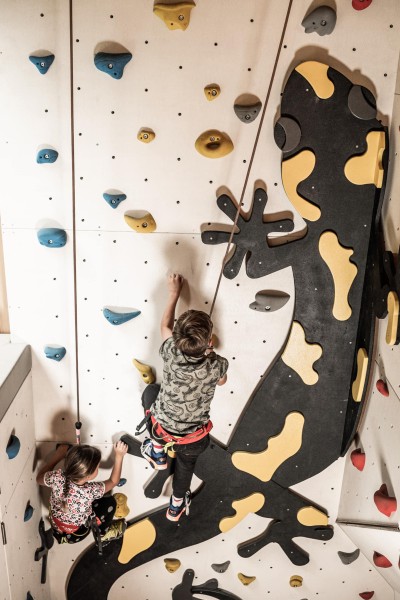 2 Kinder klettern eine Kletterwand hinauf