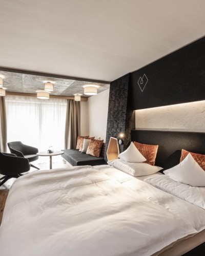 Camera d'albergo con tavolo rotondo, 2 poltrone e grande letto matrimoniale