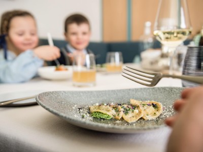 3 Schlutzkrapfen auf einem Teller und im Hintergrund 2 Kinder