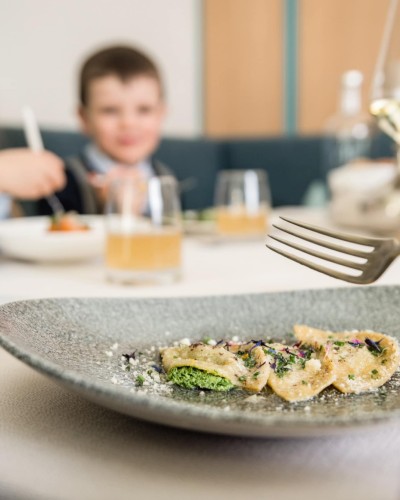 3 Schlutzkrapfen auf einem Teller und im Hintergrund 2 Kinder