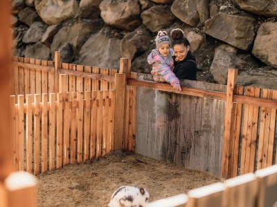 Una bambina viene tenuta in braccio da una donna e indica un coniglietto.