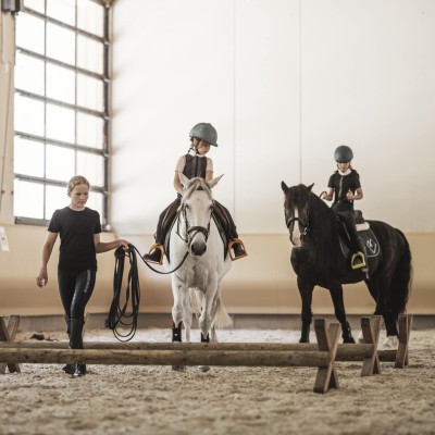 Istruttrice di equitazione conduce un cavallo con un bambino attraverso il maneggio