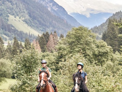 2 persone a cavallo attraversano un prato