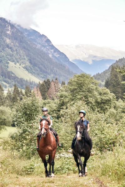 2 Personen auf Pferd reiten durch eine Wiese