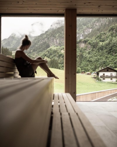 Una donna è seduta nella zona sauna e osserva l'area esterna.