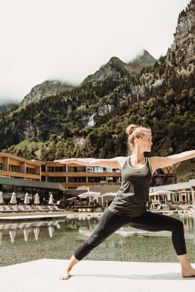 Frau praktiziert Yoga im Außenbereich des Hotels