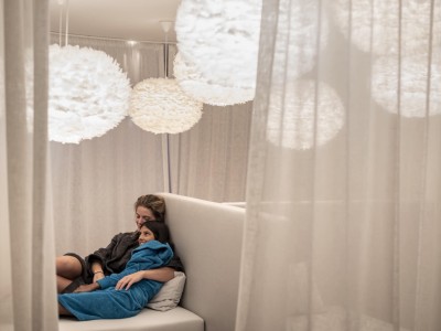 Madre e figlia sono distese rilassate l'una accanto all'altra, entrambe avvolte in un accappatoio.