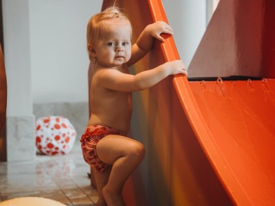 Kleinkind stützt sich an der kleinen Wasserrutsche für Kinder