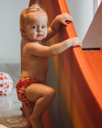 Bambino piccolo si appoggia al piccolo scivolo acquatico per bambini