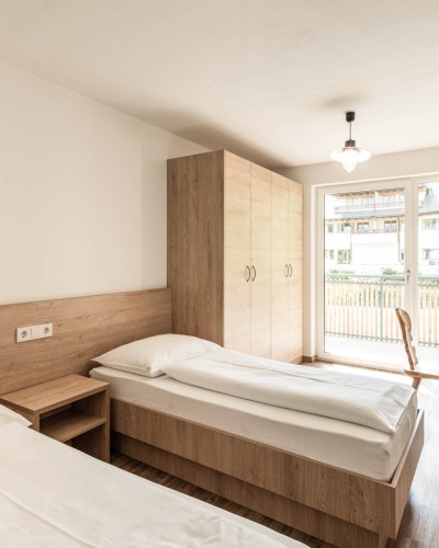 Camera da letto luminosa con due letti singoli e balcone nella casa del personale.