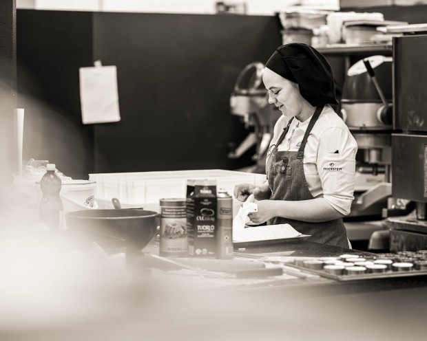 Membro della cucina che controlla un blocco note mentre lavora fra vapore in cucina.
