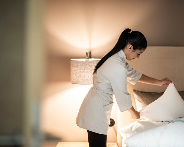 Addetta alle pulizie che sistema i cuscini su un letto nella camera al Feuerstein.