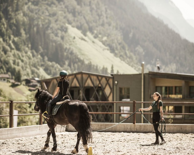 Ragazza a cavallo nel maneggio del Feuerstein mentre l’istruttrice la guida.