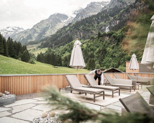 Area relax all’aperto con lettini e ombrelloni e vista sulle montagne al Feuerstein.
