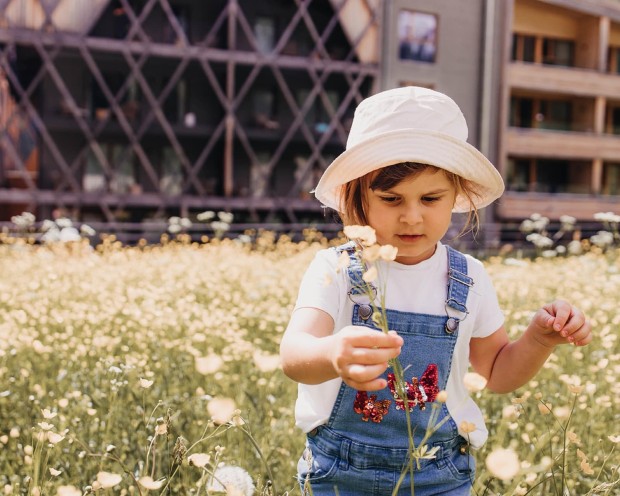 Child in flower meadow holding a flower