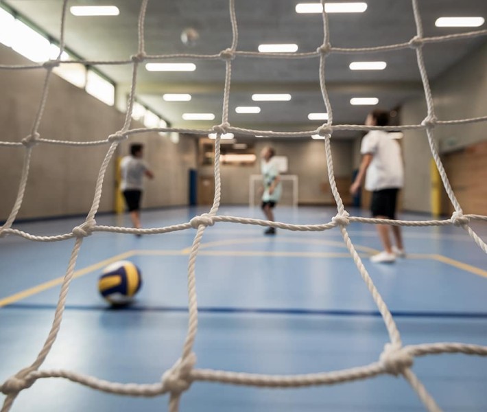 Campo da calcetto in una palestra con tre adolescenti che giocano