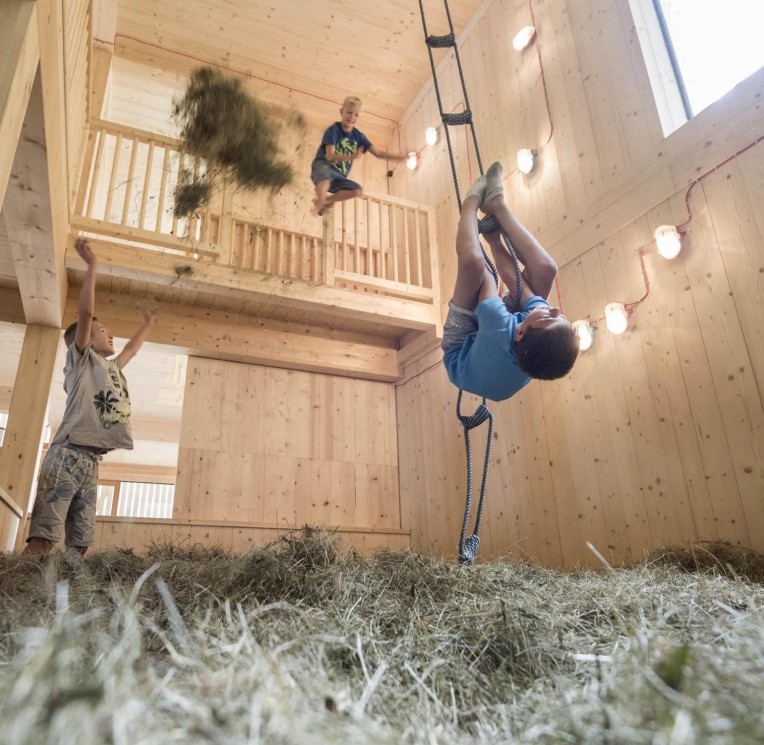 Un bambino gioca nel fienile con il fieno