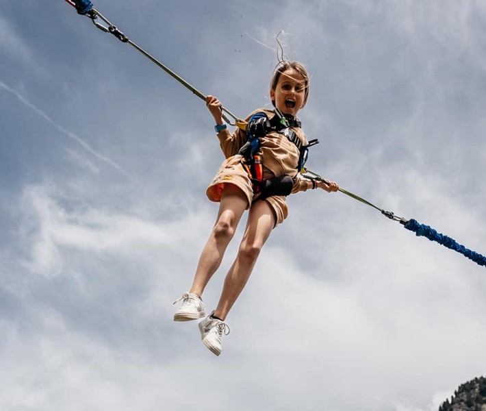 Una bambina sospesa in aria attaccata a due corde e imbracatura