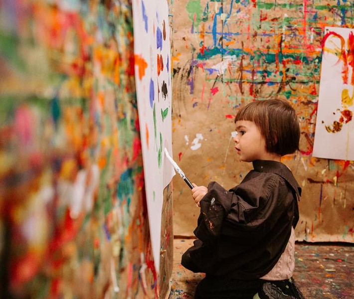 Un bambino dipinge nel laboratorio di pittura con pareti colorate