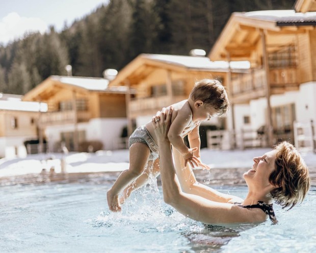 Mamma e figlio nuotano nell'Outdoor Infinity Pool del Feuerstein, il nostro Family Hotel con spa in Alto Adige