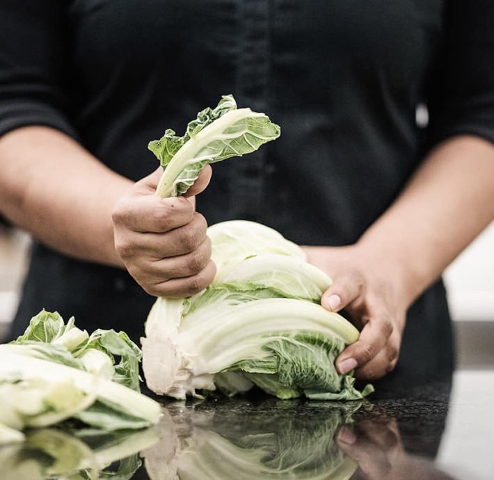 Küchin hantiert mit Gemüse in der Küche
