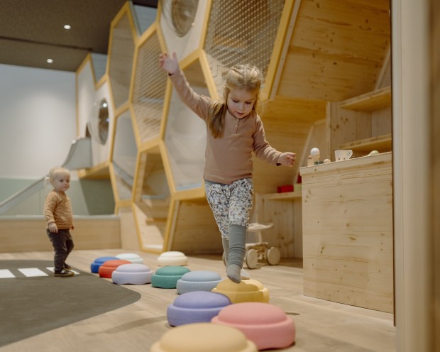 I bambini esplorano un'area giochi creativa con anelli colorati e dettagli in legno.