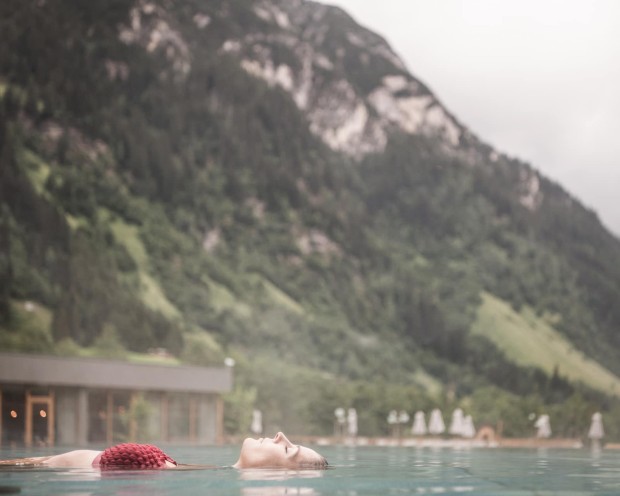 Swimming in the outdoor infinity pool of the family spa hotel Feuerstein in South Tyrol