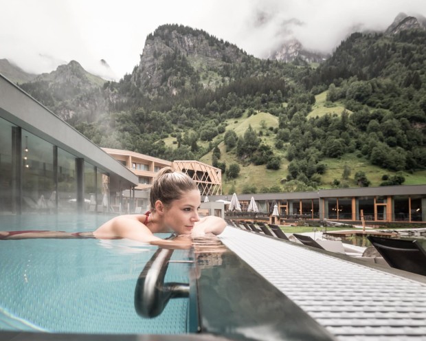Relaxing in the outdoor infinity pool of the family spa hotel Feuerstein in South Tyrol