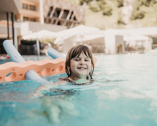 Swimming in the outdoor infinity pool of the family spa hotel Feuerstein in South Tyrol