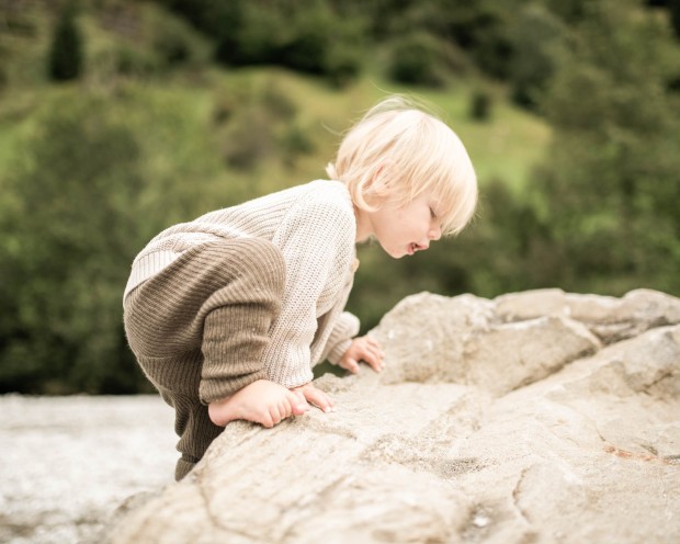 Kleiner Junge klettert auf einen Stein