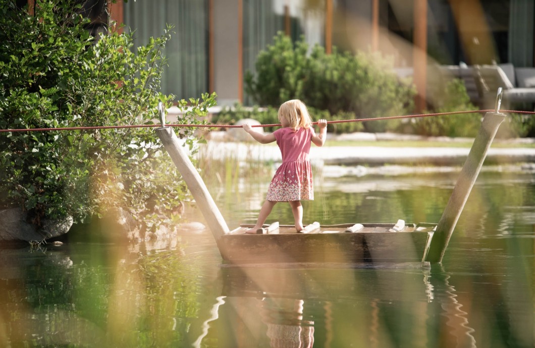 Kleines Mädchen zieht sich auf dem Floß über den See
