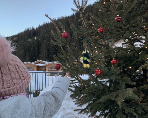 Kleines Kind zeigt auf Flammi der auf dem Christbaum hängt