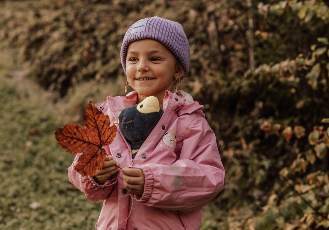 Kleines Kind mit Stofftier und großes Blatt von einem Baum