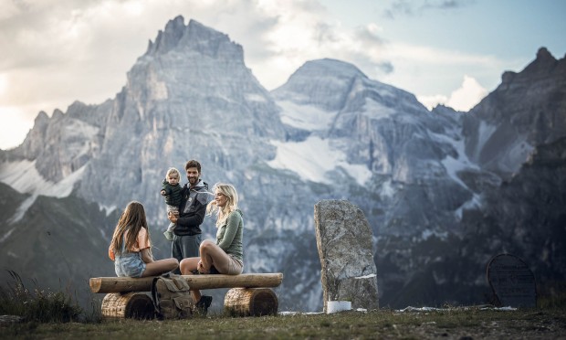 Famiglia seduta su una panchina con una montagna sullo sfondo