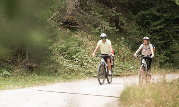 Due ciclisti pedalano su una strada sterrata nel bosco