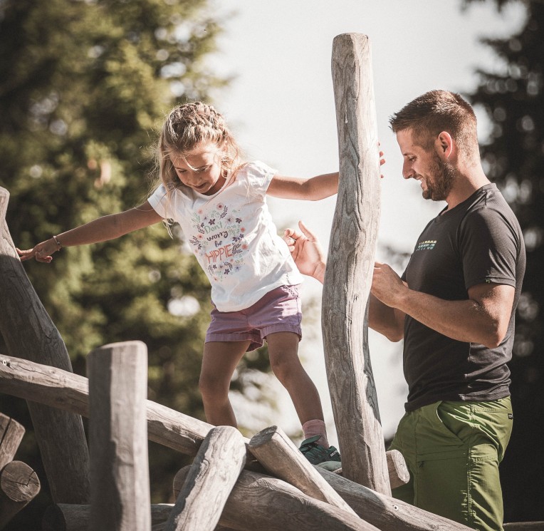 Il padre aiuta il bambino a mantenere l'equilibrio su un tronco d'albero