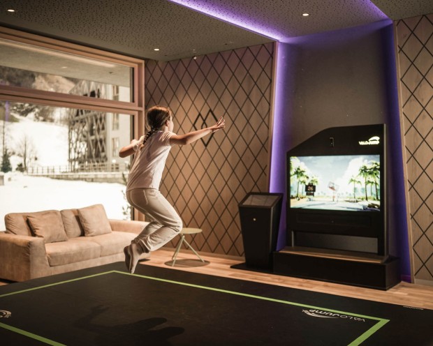 Una ragazza salta sul tappeto Valo Jump davanti a uno schermo interattivo