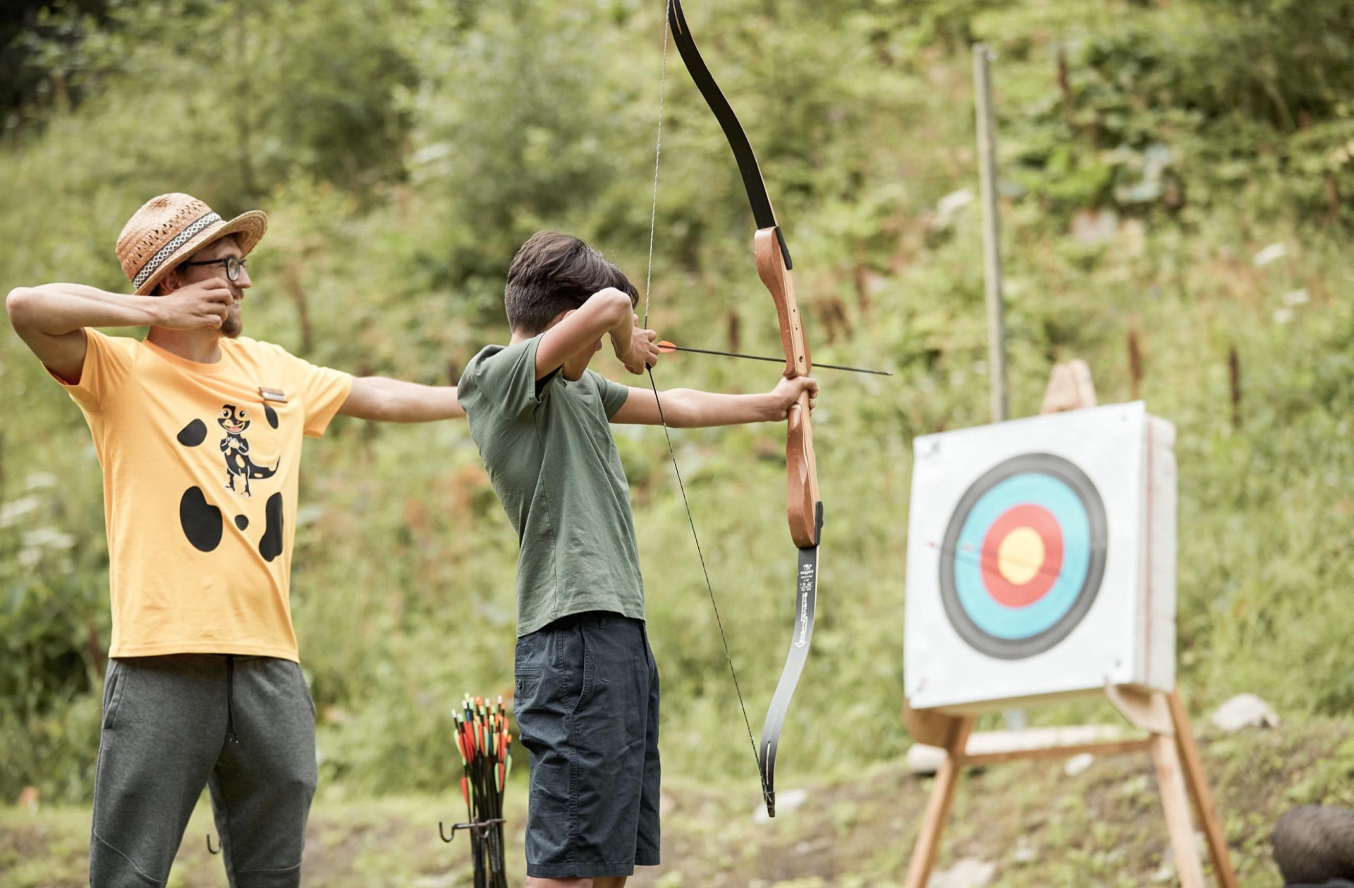Un istruttore spiega il tiro con l'arco a un adolescente