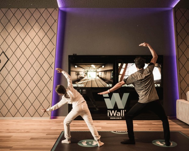 Un uomo e una ragazza giocano davanti allo schermo interattivo iWall in una sala giochi