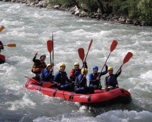 Un gruppo di ragazzi fa rafting su un gommone in un fiume impetuoso
