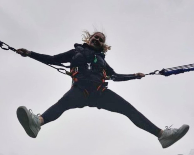 Un adolescente salta su un trampolino bungee con braccia e gambe distese
