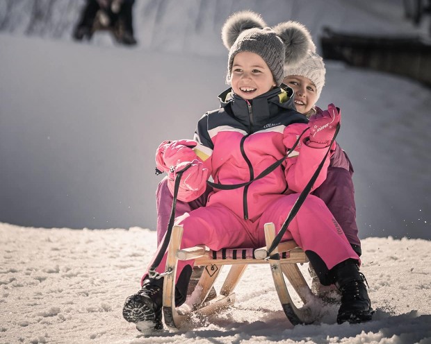 Sledging in the garden of the Feuerstein family hotel, the ideal place for a family holiday in the mountains